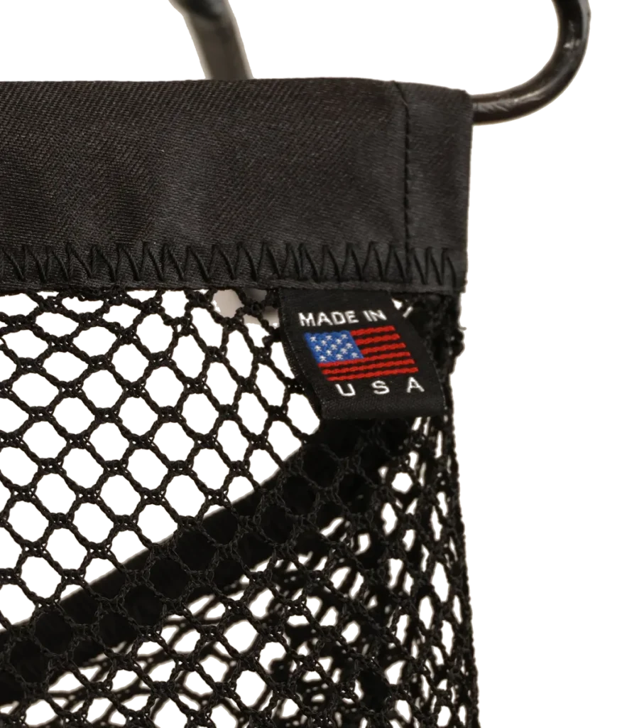 Wall-mounted bathroom storage unit metal sculpture with rolled white towels in a steel wire basket, a black polyester mesh removable laundry bag for soiled hand towels hanging below from a steel hanger and incorporating a dock side theme with a decorative steel dragonfly, copper and brass reed accents and steel birds in flight from a brass dock pier.