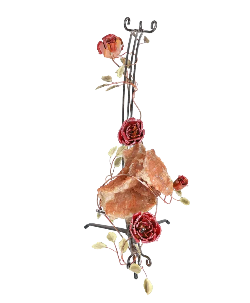A handcrafted metal sculpture featuring a large open quartz geode nestled in the center. The open geode is supported in a semi-circular steel structure. Several copper roses and brass leaves embellish the structure, which has a metal base for stability.