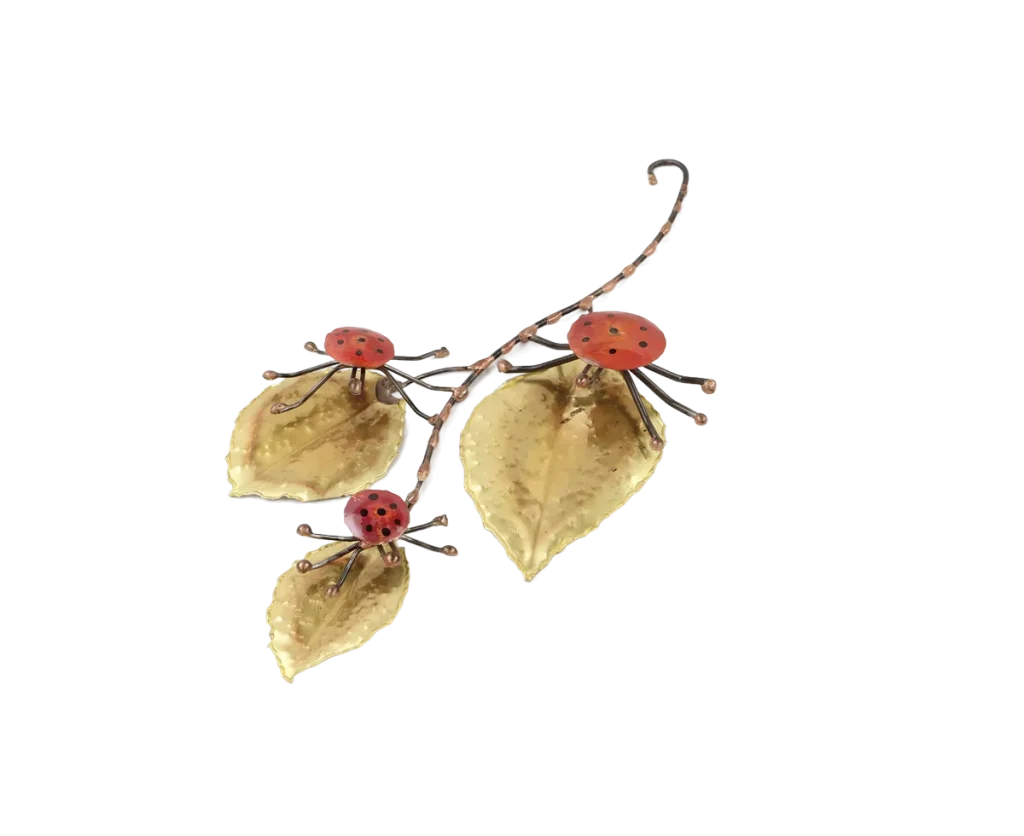 Freestanding metal sculpture showing three copper and steel ladybugs poised on the large brass leaves of a leafy branch