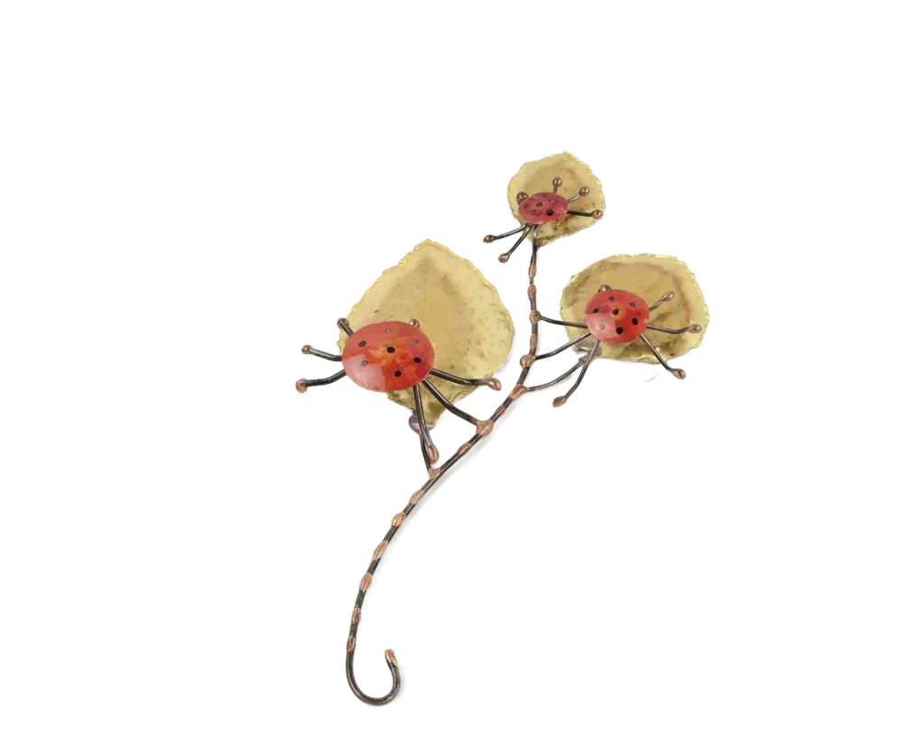 Freestanding metal sculpture showing three copper and steel ladybugs poised on the large brass leaves of a leafy branch