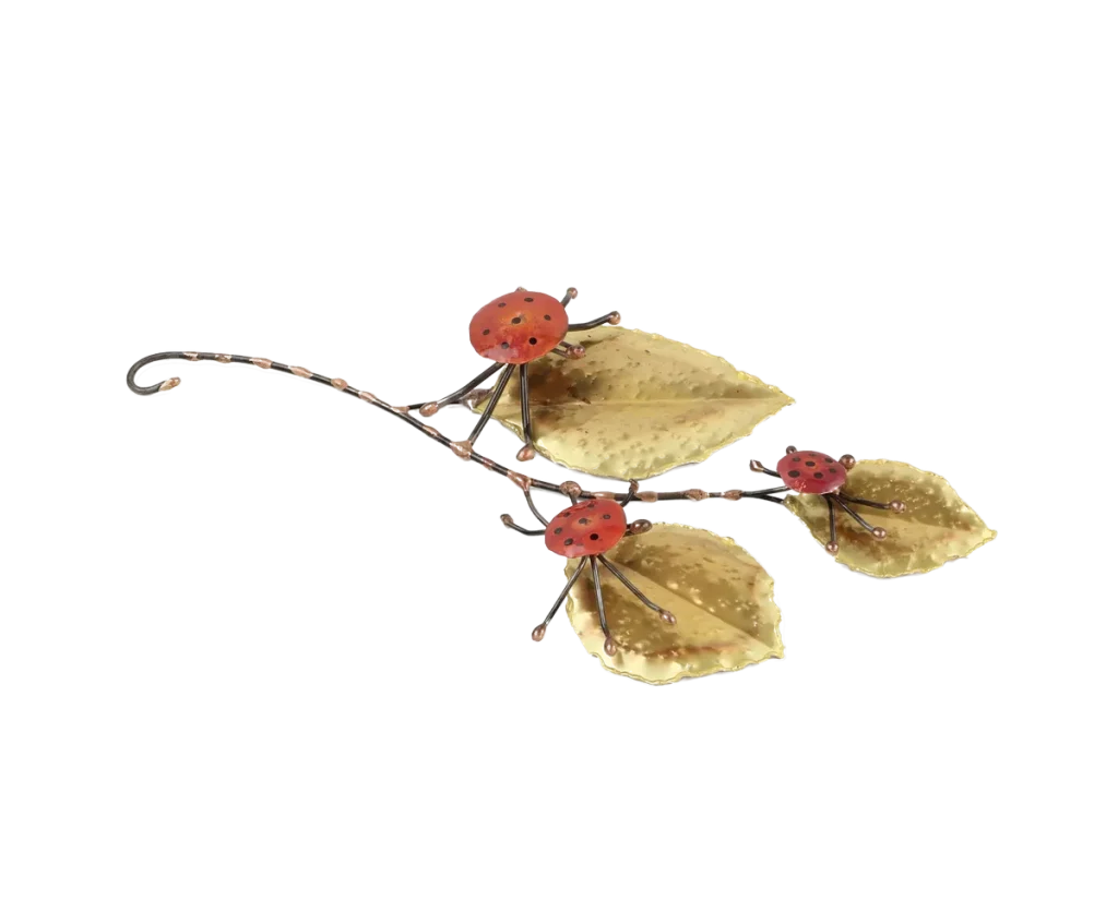 Freestanding metal sculpture showing three copper and steel ladybugs poised on the large brass leaves of a leafy branch