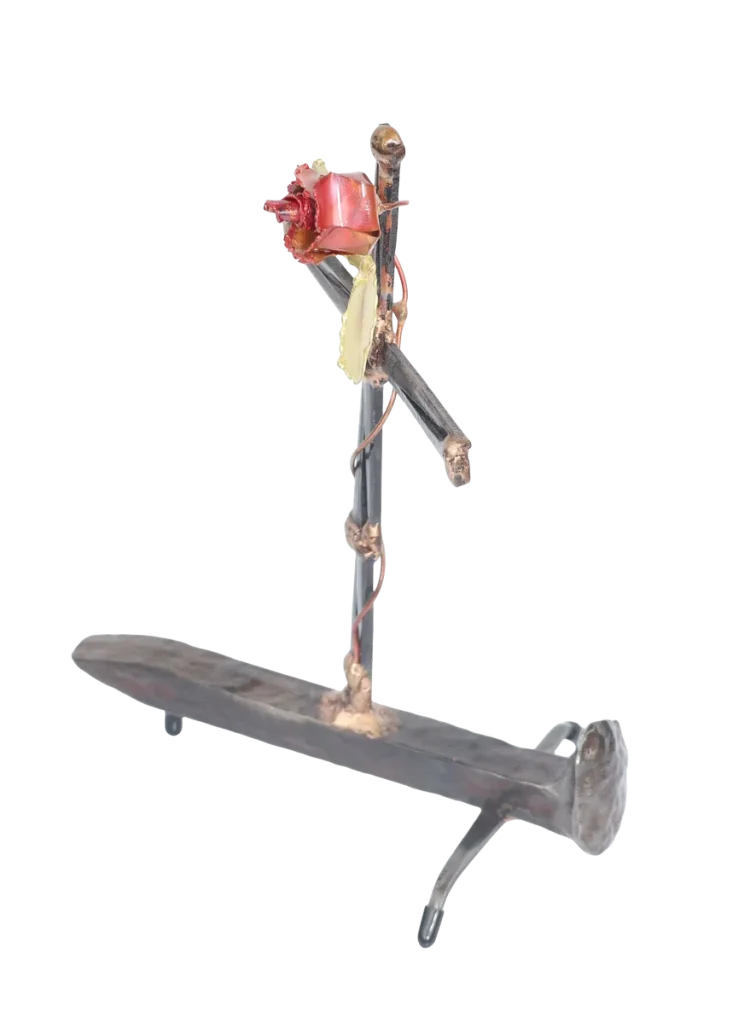 Handcrafted metal cross made of steel cut nails and mounted on a railroad spike, with a decorative copper rose, copper vine and brass leaves twisted around the cross from its base.