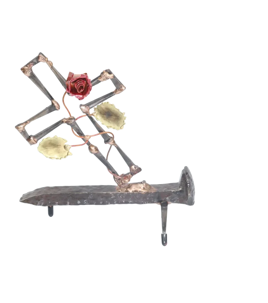 Freestanding metal sculpture depicting a broken cross made of cut steel nails and mounted on a railroad spike with a copper rose and vine with brass leaves, growing out of the break in the cross. The broken cross and rose is symbolic of the resurrection of Jesus after crucifixion.
